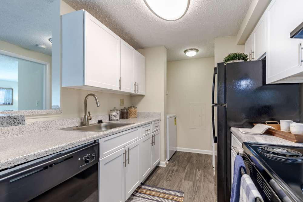 A kitchen with white cabinets and black appliances at Kingscrest Apartments in Frederick, Maryland