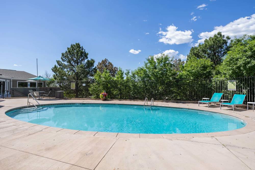 Swimming Pool Area with a Pair of Beach Chair at The Knolls at Sweetgrass Apartment Homes in Colorado Springs, Colorado.