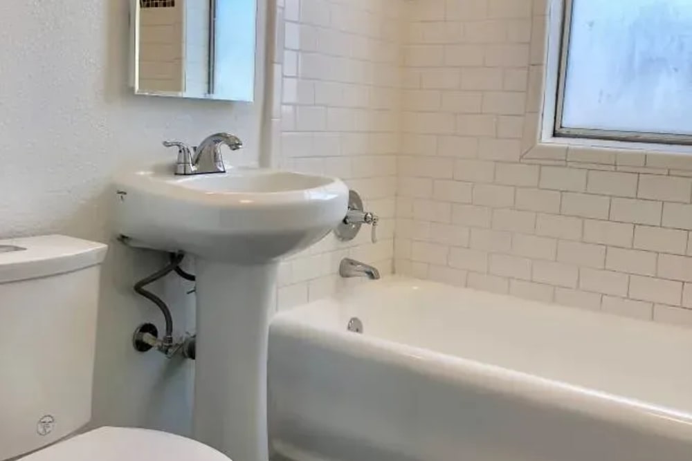 A clean bathroom featuring a sink, bathtub and commode at Westmoreland Apartments in Los Angeles, California