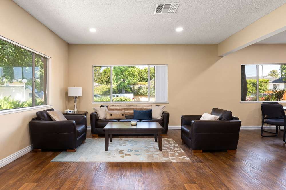  Resident seating area with large chairs, coffee tables, and large windows at Reseda Village Green in Reseda, California