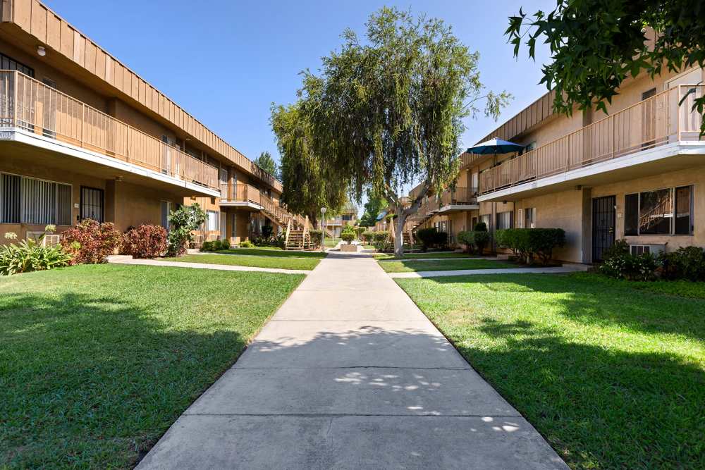 View of exterior of apartments and green lawn at Reseda Village Green in Reseda, California