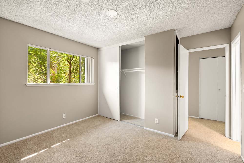A well-lit bedroom with beige carpet and view of wooden balcony at Reseda Village Green in Reseda, California