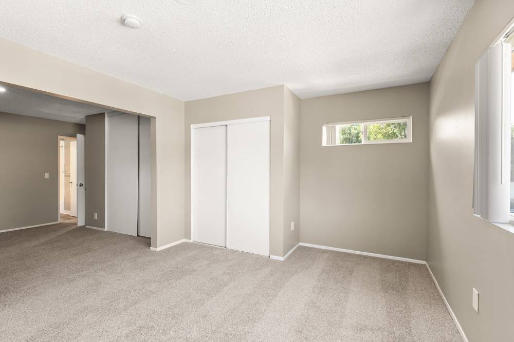 Open layout carpeted living room with plenty of room for a couch, coffee table, and more at Reseda Village Green in Reseda, California