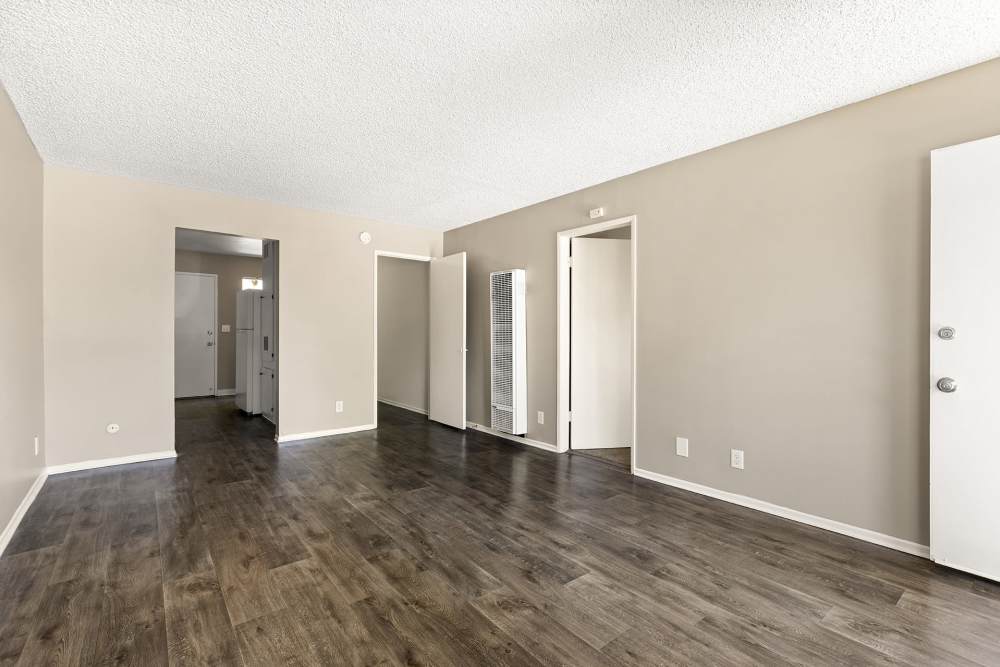 Open layout living room and connecting dining room with hard-wood style flooring and plenty of room at Reseda Village Green in Reseda, California