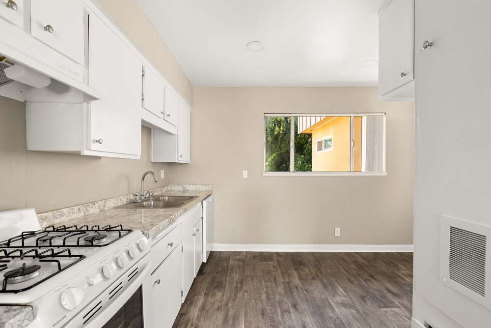 Kitchen with island, stove, and wood cabinetry at Reseda Village Green in Reseda, California