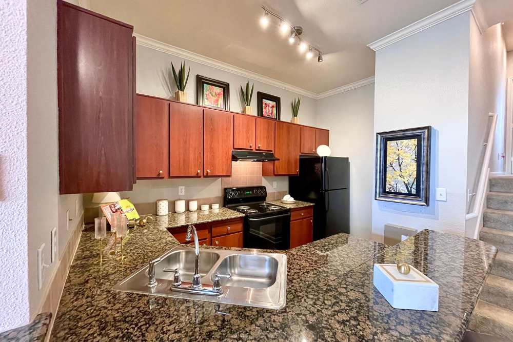 Model kitchen with range, fridge and wooden cabinets at The Abbey at Stone Oak in San Antonio, Texas