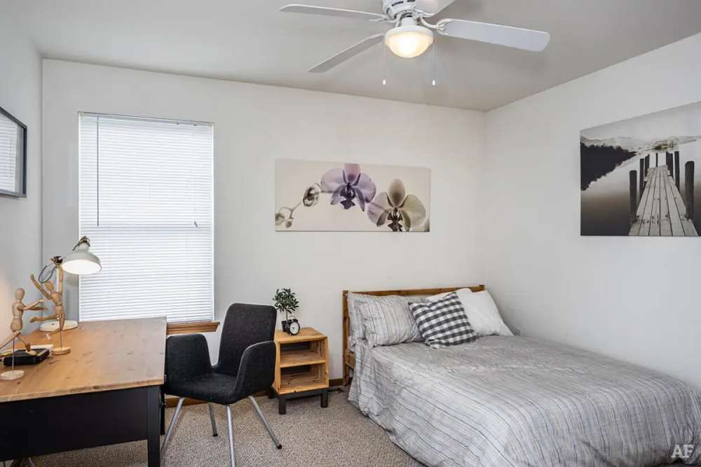 Vibrant bedroom with side table and ceiling fan at Cross Creek Villas in Columbia, Missouri