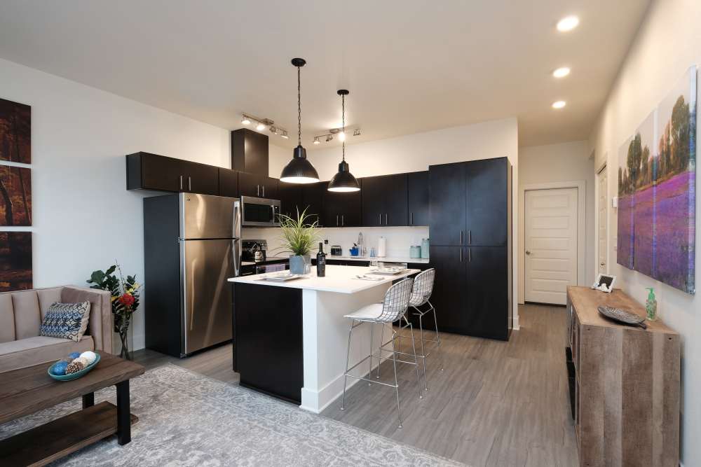 Open layout of kitchen and living room with granite-countertop bar, and stainless steel sink and dishwasher at 27 Elm in Redmond, Oregon, 