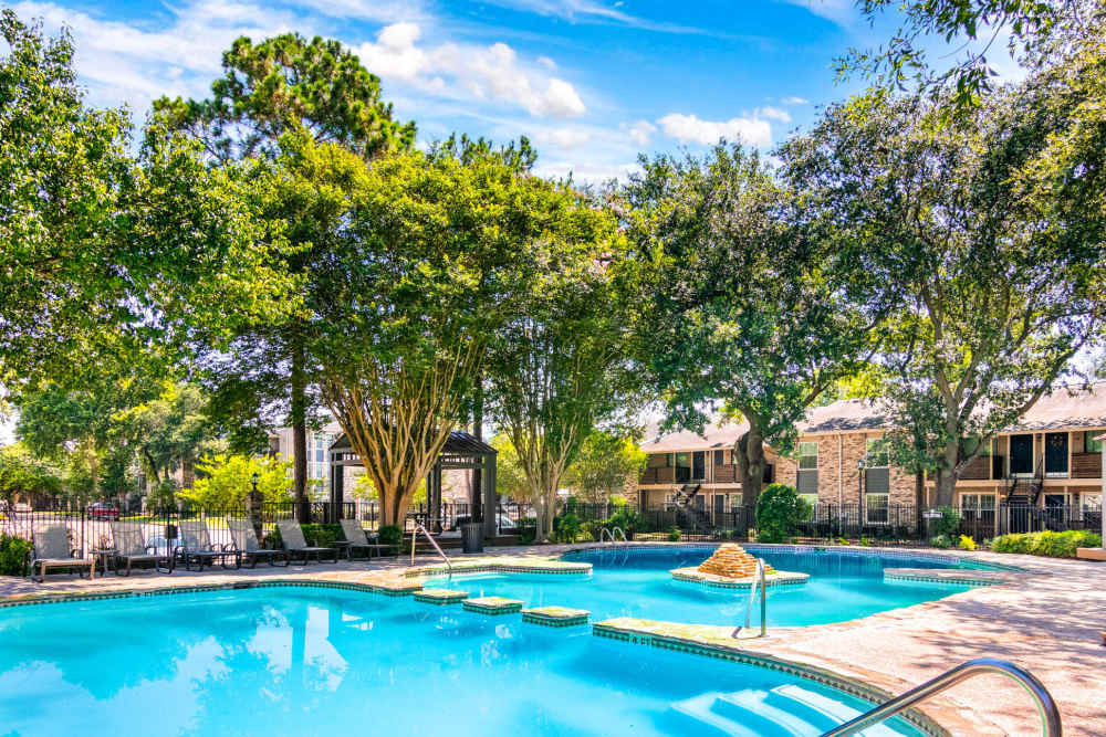Large swimming pool with lots of tree around at The Abbey At Enclave in Houston, Texas