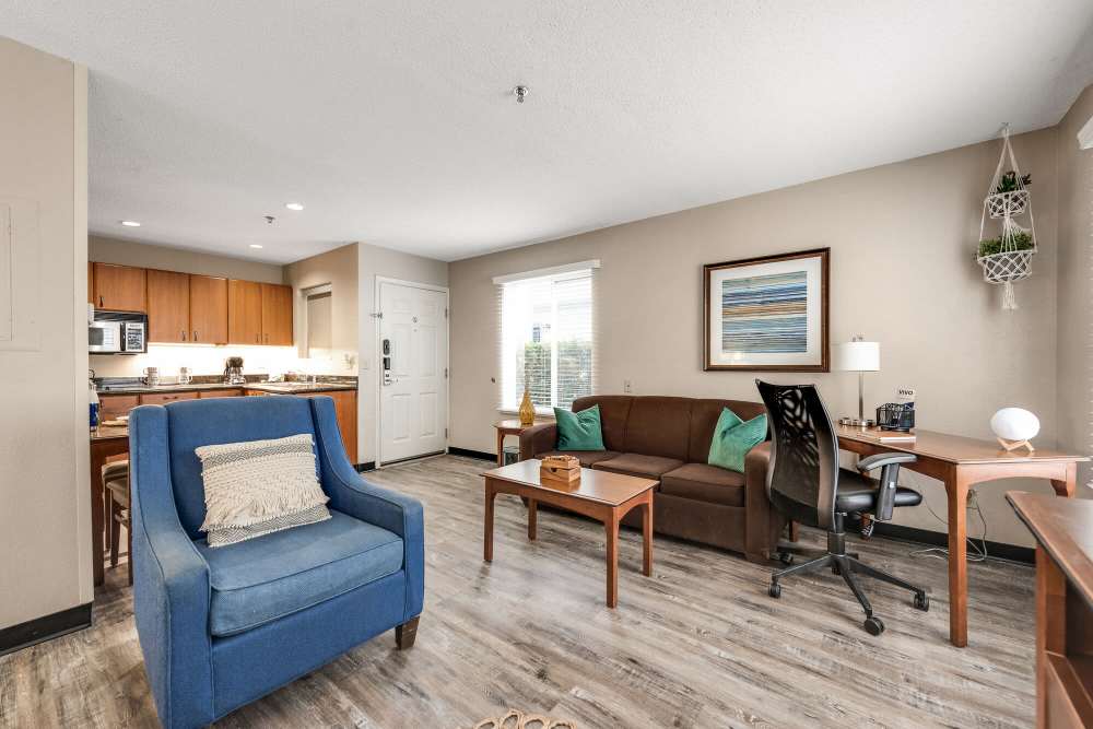 Spacious living room with couch, coffee table, chairs, wood-style flooring and open layout connecting to kitchen at Vivo Living Charlotte in Charlotte, North Carolina, 