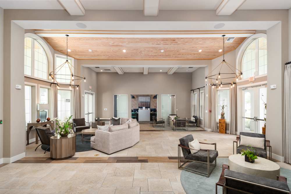 Modern design clubhouse with large lounge chairs and televisions at Shadetree Apartments in Ruskin, Florida