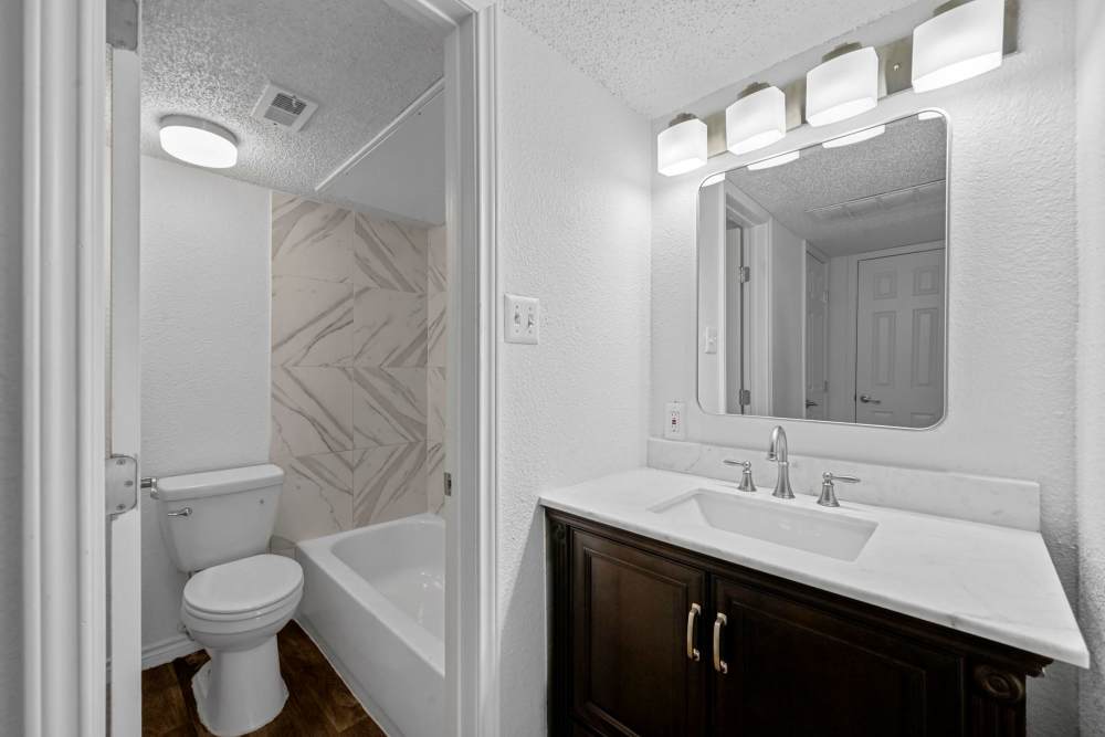 Bathroom with mirror, commode and mirrors at Broadmoor Place in Irving, Texas