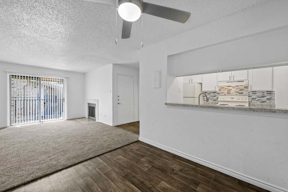 Plush carpeted living room with a view of kitchen at Broadmoor Place in Irving, Texas