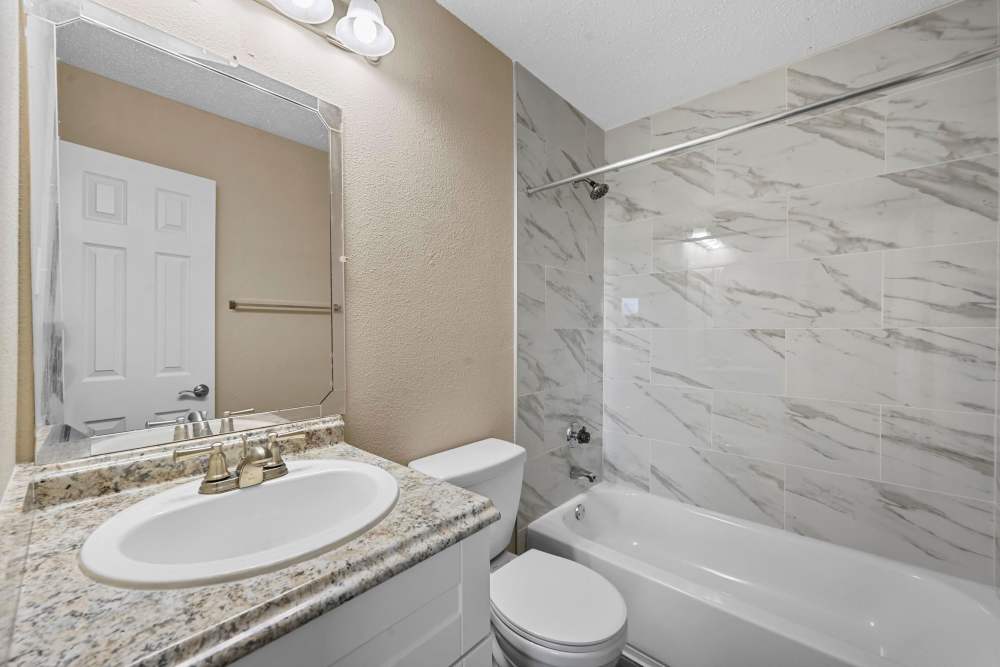 Bathroom with mirror, tub and sink at Village Square in Irving. TX
