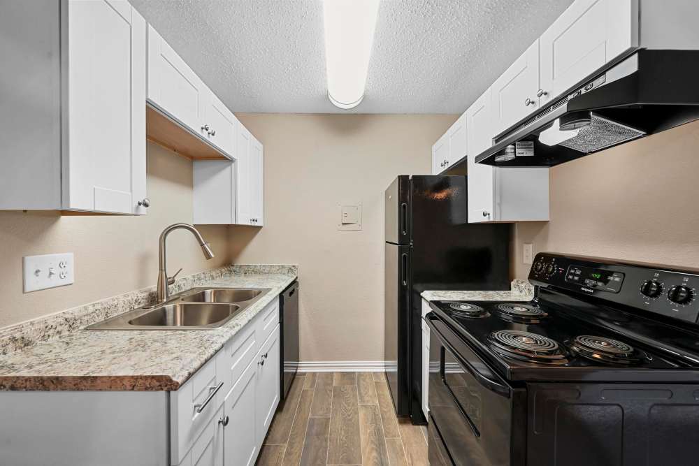 Kitchen with refrigerator, sink, and storage space at Village Square in Irving. TX