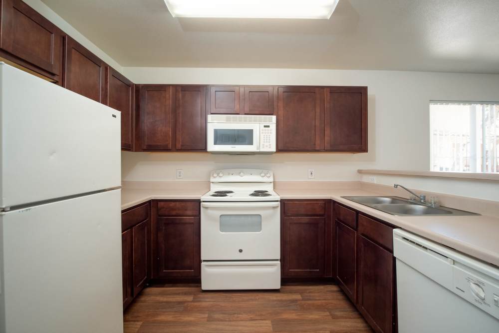 Kitchen with wood-style flooring and white appliances at Steeple Chase Apartments in Peoria, Arizona