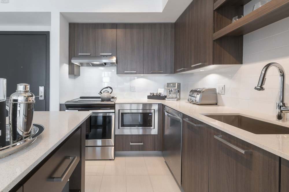 Cozy apartment kitchen with tan colored cabinetry and stainless-steel appliances at Solitair Brickell Apartments in Miami,Florida
