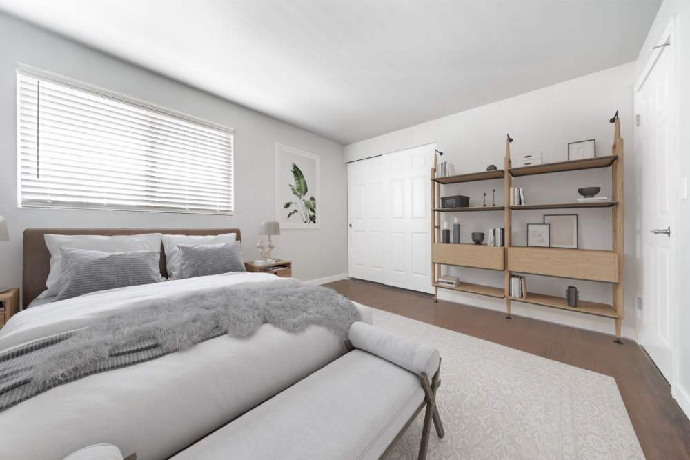 Modern bedroom with a bed, nightstand, bench and a bookshelf at Lantera Apartments in Seattle, Washington