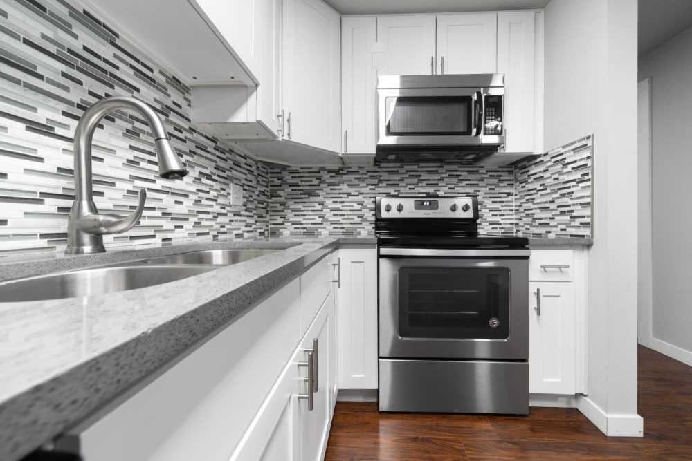 Kitchen with wooden cabinets, microwave and granite countertops at Lantera Apartments in Seattle, Washington