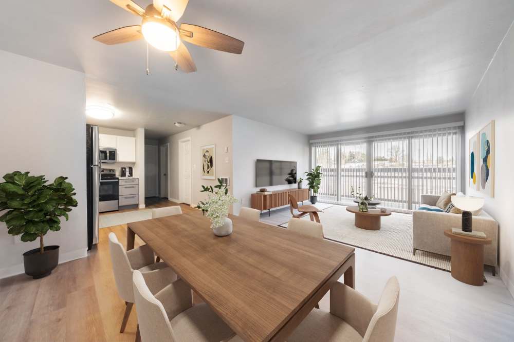 Open-concept dining and living room area with a wooden table, couch in the living room and a large TV at Lantera Apartments in Seattle, Washington
