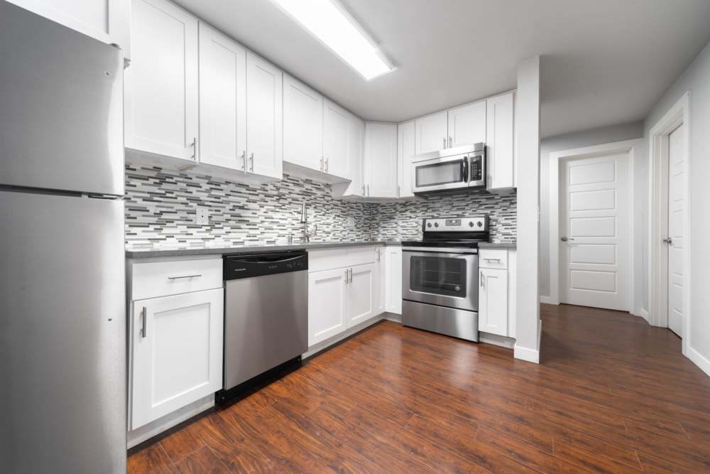 Spacious kitchen with hardwood flooring, granite countertops, stainless-steel appliances and a refrigerator at Lantera Apartments in Seattle, Washington