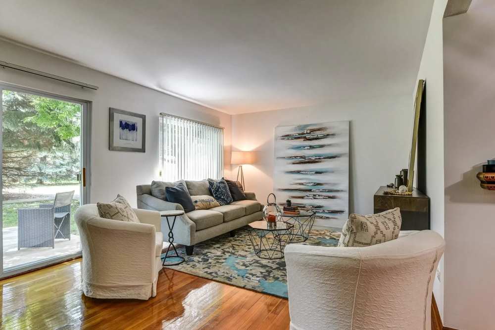 Spacious living room with chairs, coffee table and access to patio through door with glass window at Park Ridge Commons in Des Plaines, Illinois