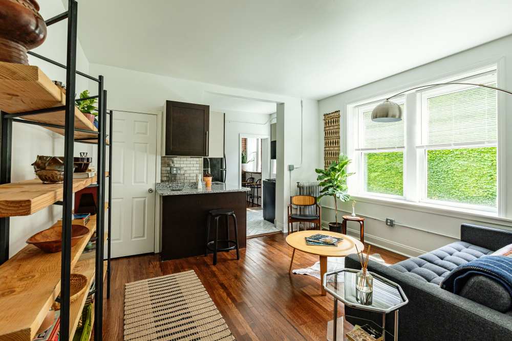 Brightly lit and open living room with large window at Detroit Living in Detroit, Michigan