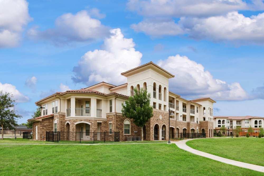 View of apartment exterior with lush green at Renaissance At North Park in Lubbock, Texas
