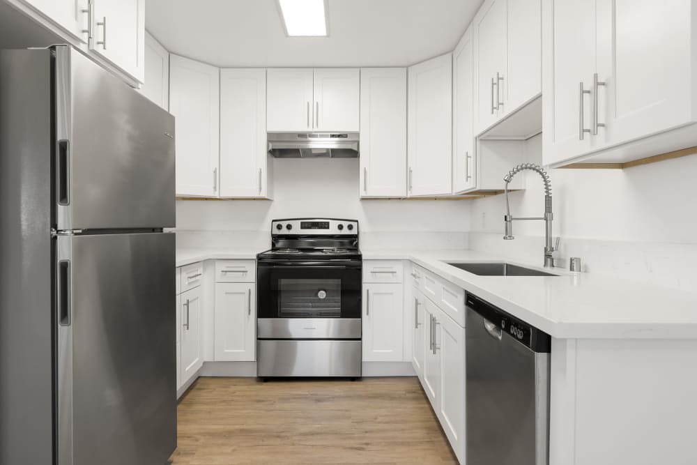 A modern kitchen featuring stainless steel appliances and sleek white cabinets at Park in Escondido, California