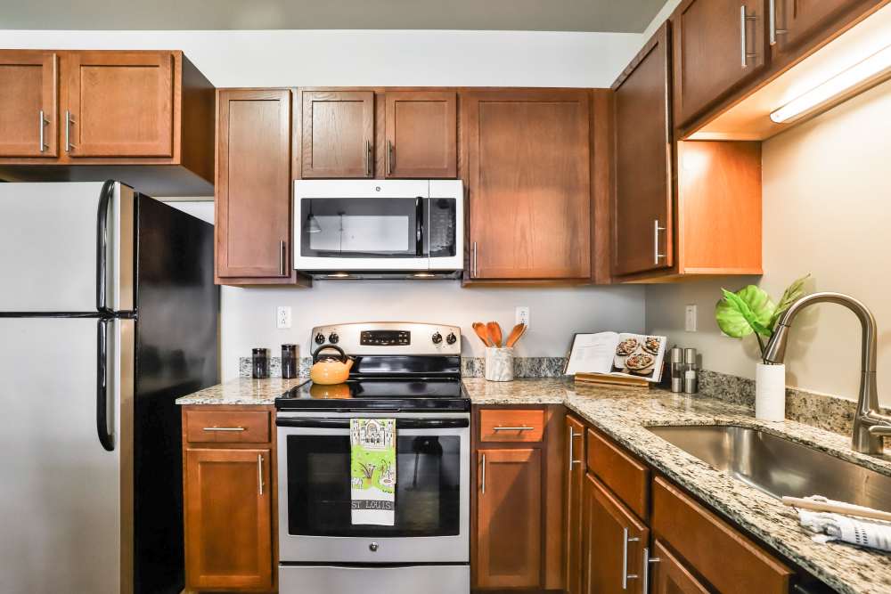 Kitchen with walnut color cabinets  at Residences at The Streets of St. Charles Apartment Homes in Saint Charles, Missouri