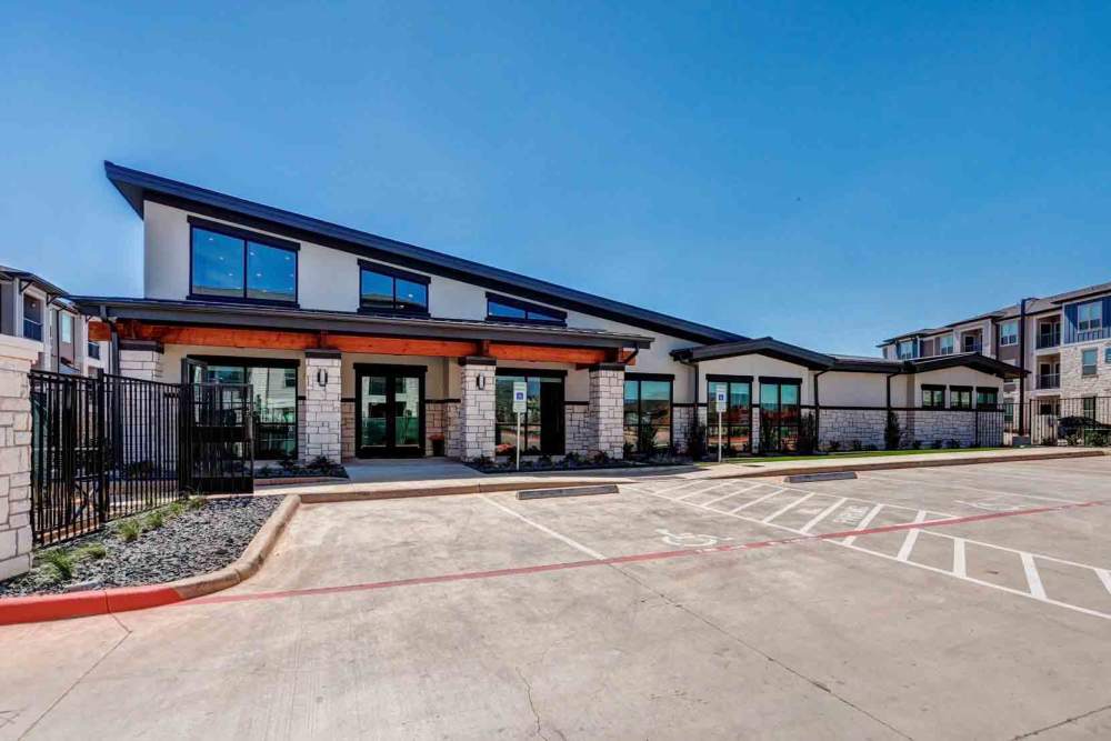 Modern apamart building with a sloped roof sits adjacent to a parking lot at The Abbey at Veramendi in New Braunfels, Texas