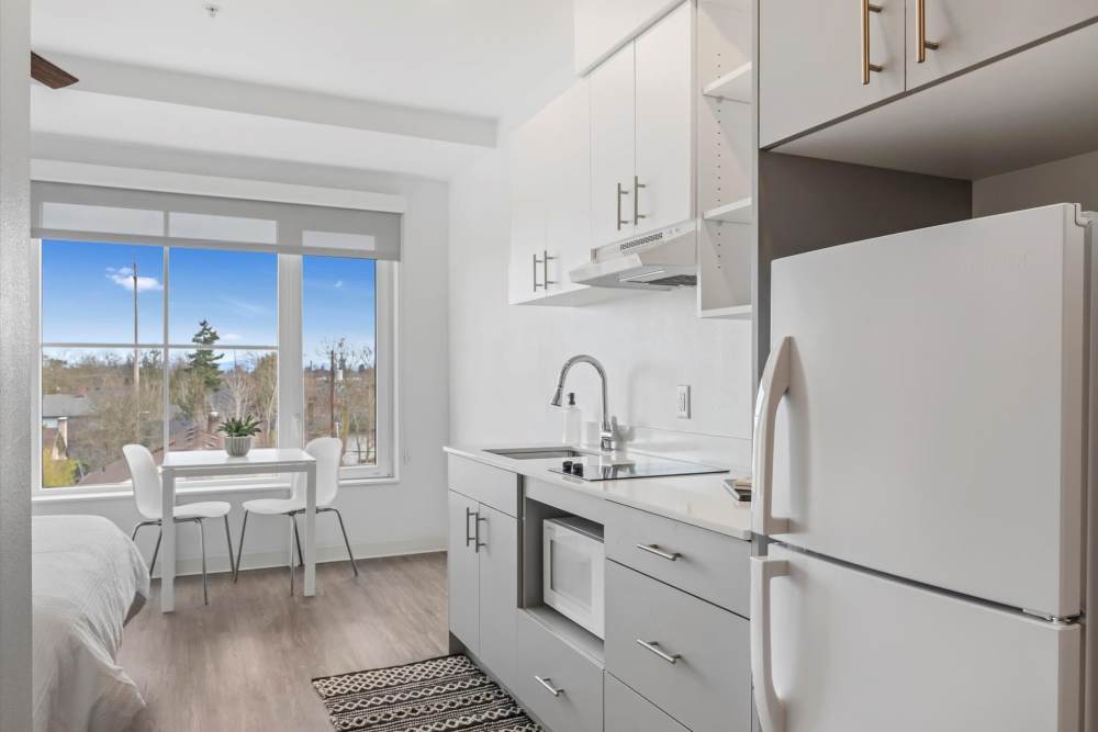 Modern kitchenette with white cabinets, grey countertops, and appliances at Koz on Killingsworth in Portland, Oregon