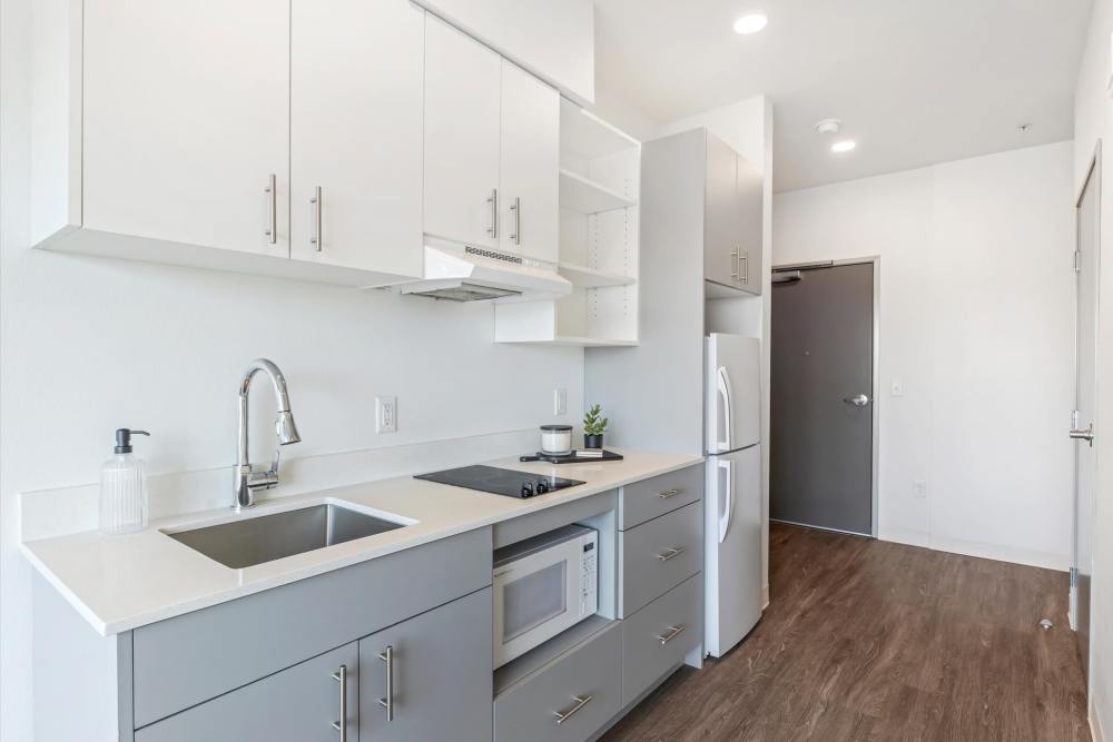 Modern kitchen with gray cabinets, white countertops, sink, stovetop, and microwave at Koz on Killingsworth in Portland, Oregon