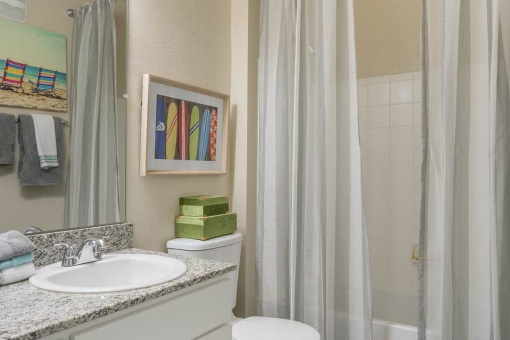 Bathroom with a bathtub, toilet and large mirror at The Haven At West Melbourne in West Melbourne, Florida