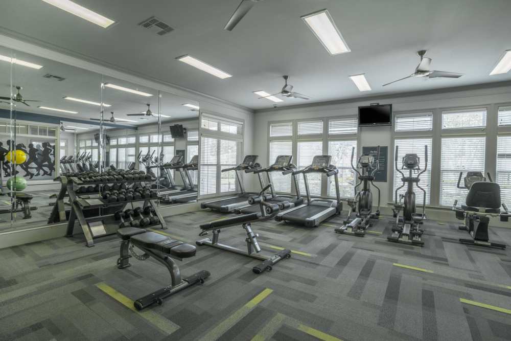 Well-equipped fitness center with large windows at The Haven At West Melbourne in West Melbourne, Florida