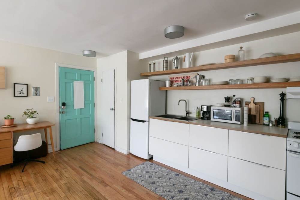 Fully-equipped kitchen with refrigerator and white cabinets at Detroit Living in Detroit, Michigan