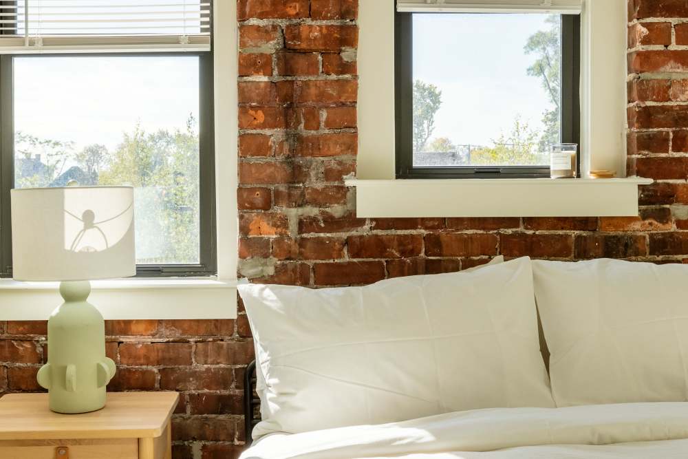 Bright bedroom with white bed and windows behind the bed at Detroit Living in Detroit,Michigan