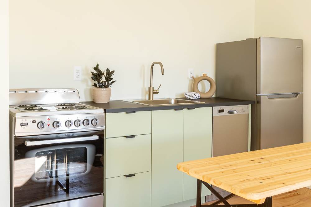 Cozy kitchen with light green toned cabinetry and appliances at Detroit Living in Detroit,Michigan