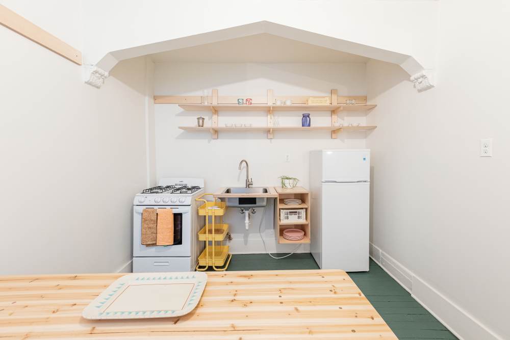 Kitchen with a wooden table, refrigerator and green flooring at Detroit Living in Detroit,Michigan