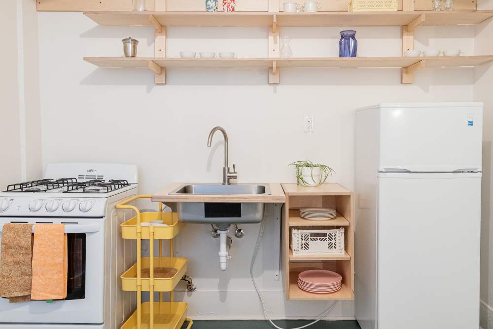 Compact apartment kitchen with a white refrigerator, stove and sink at Detroit Living in Detroit,Michigan