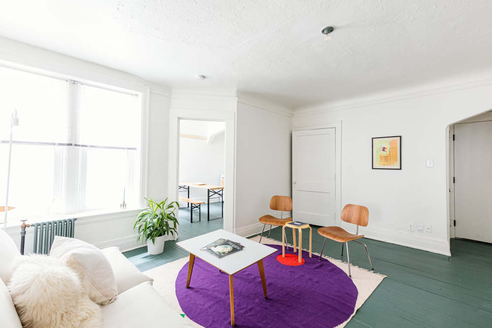 Spacious living room with purple rug beneath the table at Detroit Living in Detroit,Michigan
