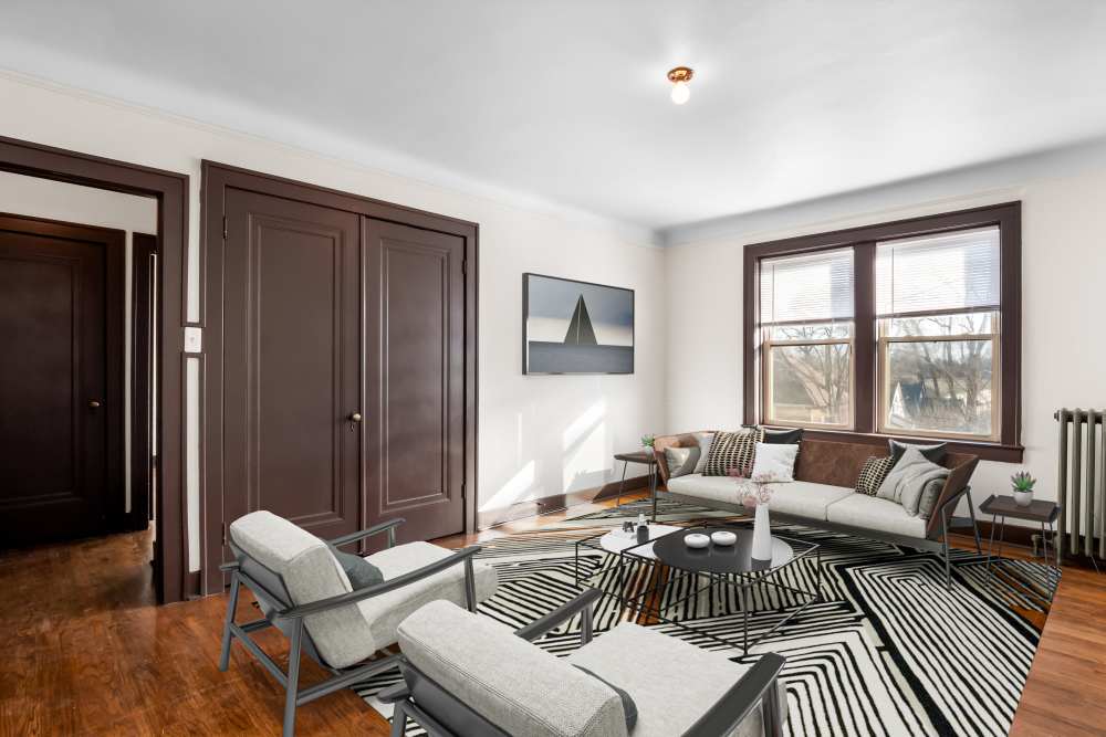 Open layout living room and connecting dining room with hard-wood style flooring and plenty of room for a couch and more at Detroit Living in Detroit, Michigan