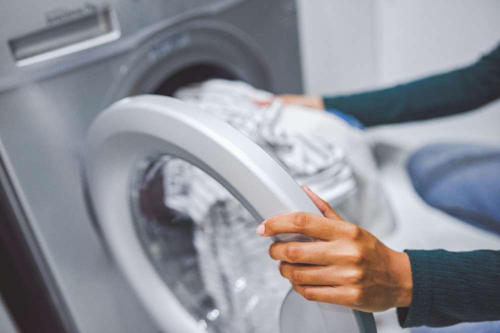 Women put cloth in washer at Detroit Living in Detroit, Michigan