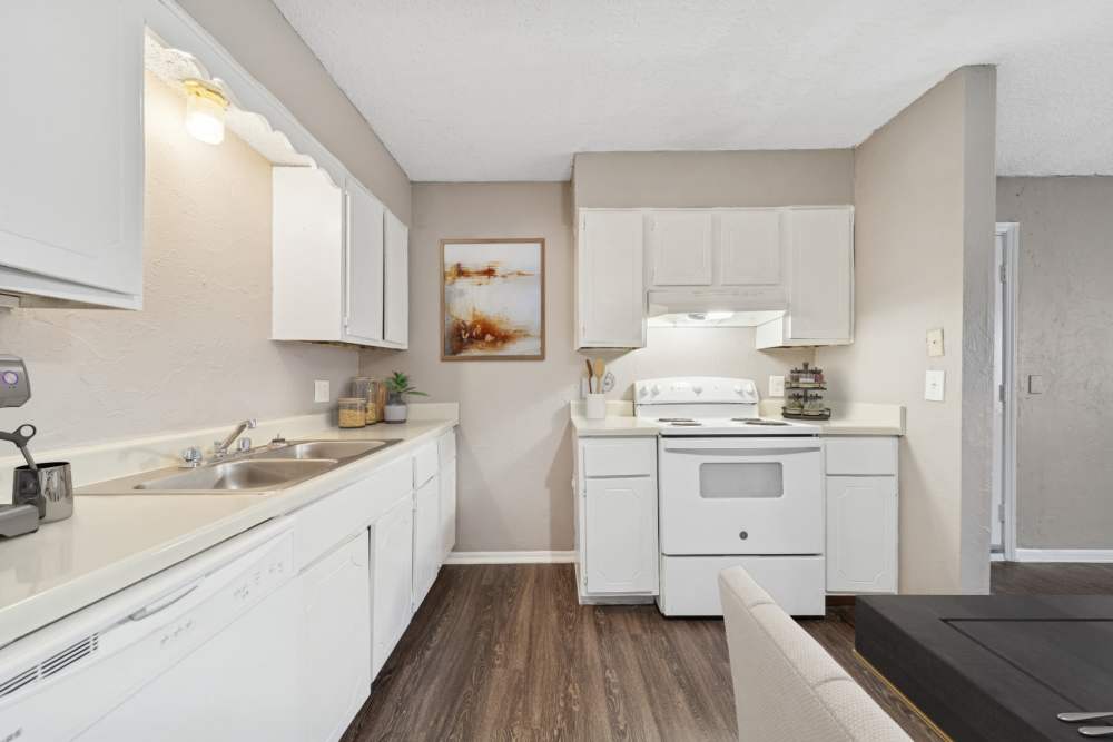 Dining area showcasing the kitchen with sink, appliances and white hardwood cabinets at Cypress Point Apartments in Shawnee, Oklahoma