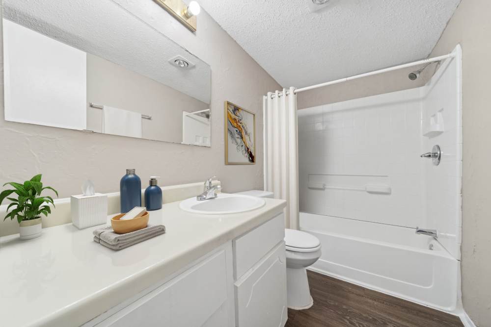 Spacious comfort room with long mirror and curtained bath tub at Cypress Point Apartments in Shawnee, Oklahoma
