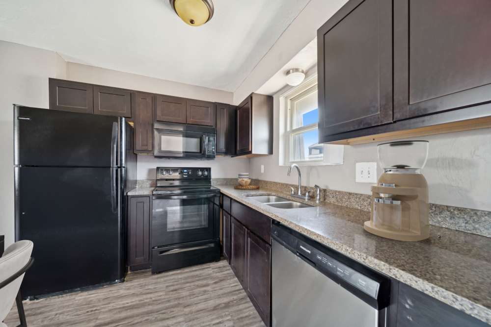 Kitchen area showcasing the kitchen bar with appliances and hardwood hanging cabinets at Vintage At 50th in Oklahoma City, Oklahoma