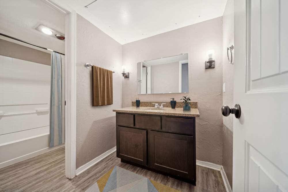 Bathroom with curtained bathtub and sink with mirror at Vintage At 50th in Oklahoma City, Oklahoma