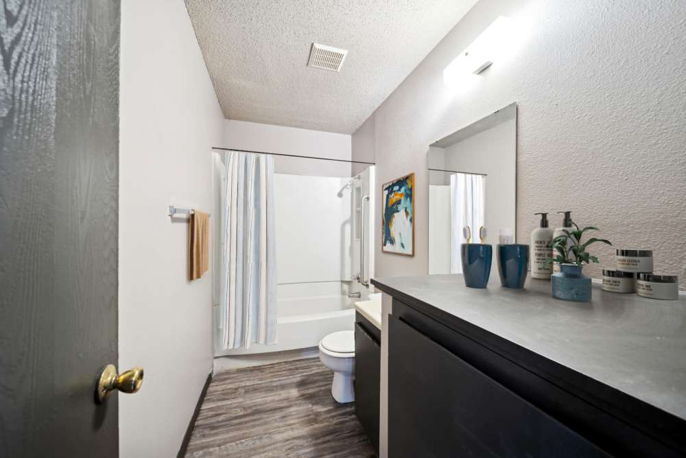 Bathroom with curtained bathtub and a toilet bowl at Sherwood Pointe Apartments in Shawnee, Oklahoma
