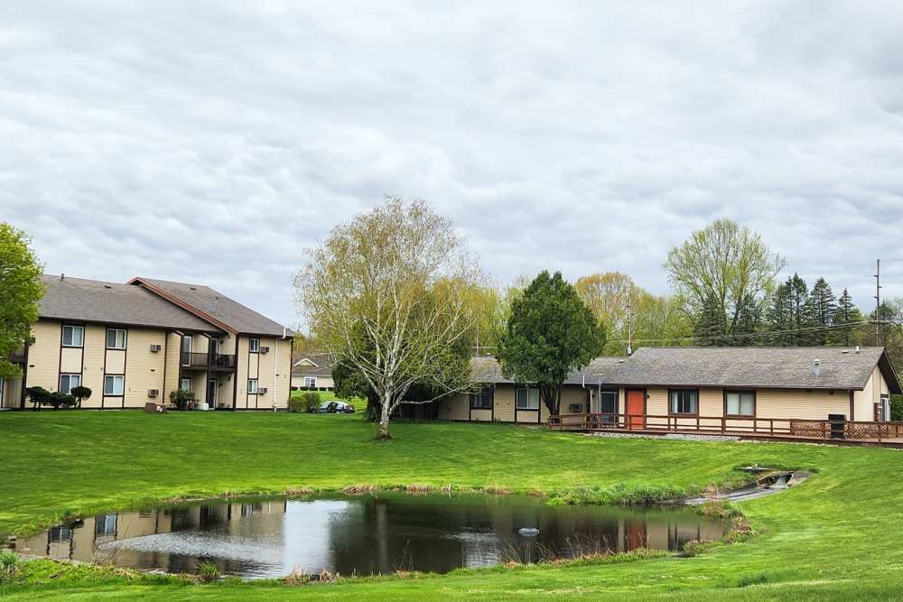 Beautiful view of lake, surrounding green grass and trees right outside apartments at Mill Pond Apartments (Buchanan) in Buchanan, Michigan