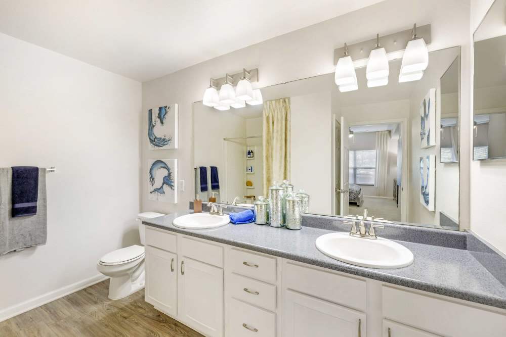 Spacious bathroom with a toilet, large mirror and storage units at Eastland Trails in Independence, Missouri